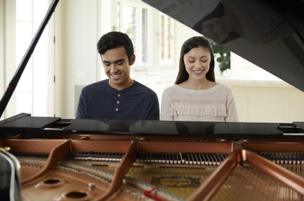Couple playing a Yamaha grand piano together